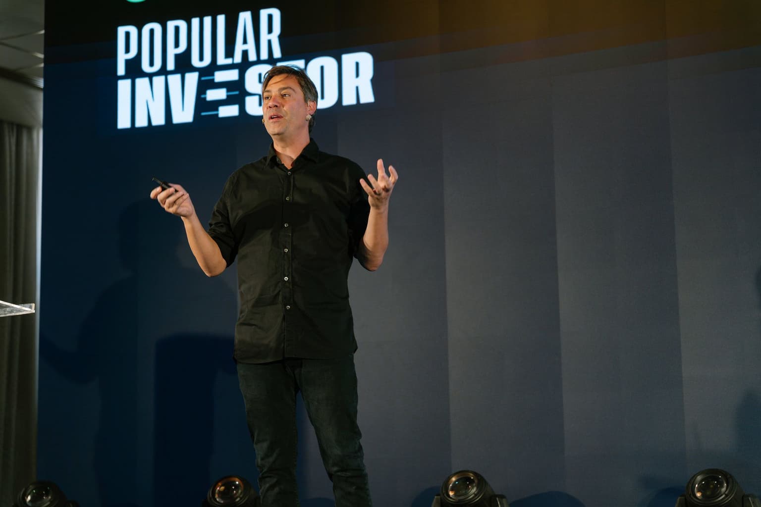 Yoni Assia on stage in front of the Popular Investor backdrop